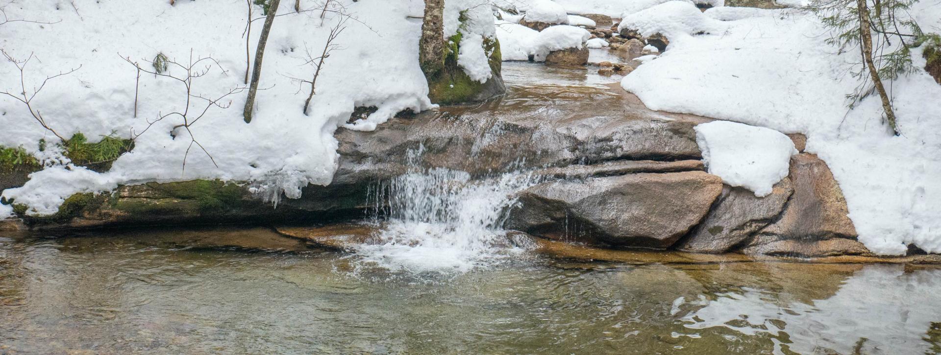 A flowing river surrounded by snow