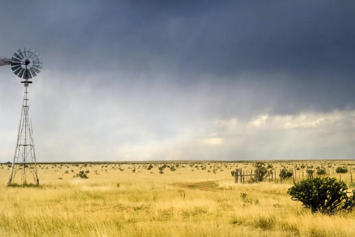 A windmill in a field before a storm in the Southern Plains.