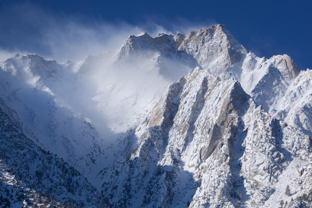 Wind blows snow off of steep, snow-covered peaks in the eastern Sierra Nevada. 